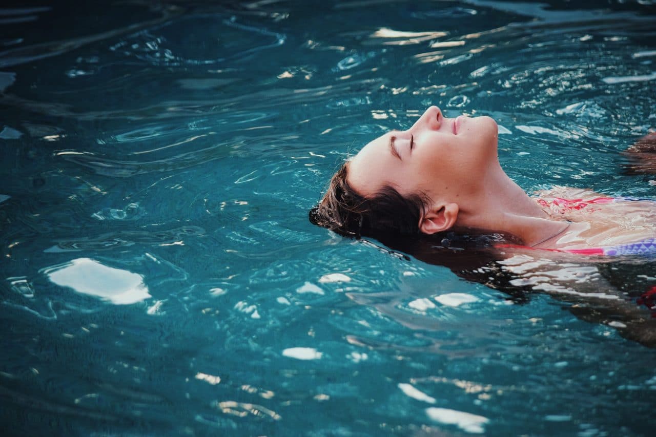 Woman relaxing and floating on her back in the pool.