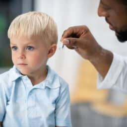 Audiologist inserts a hearing aid onto a child.