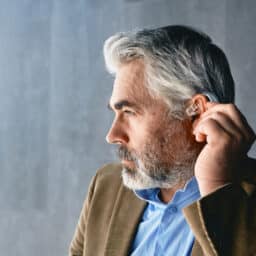 Man places hearing aid over his ear