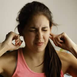 Woman with tinnitus holds ears