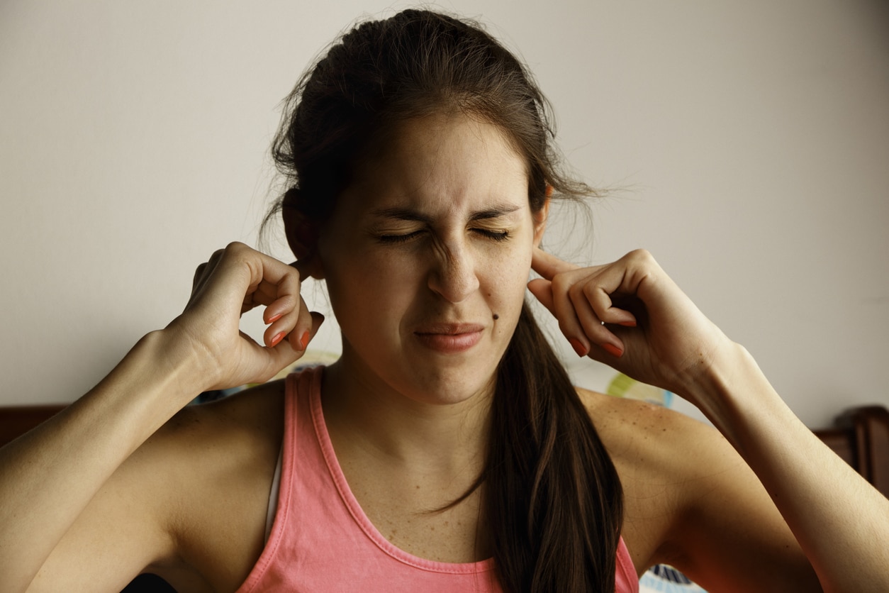Woman with tinnitus holds ears