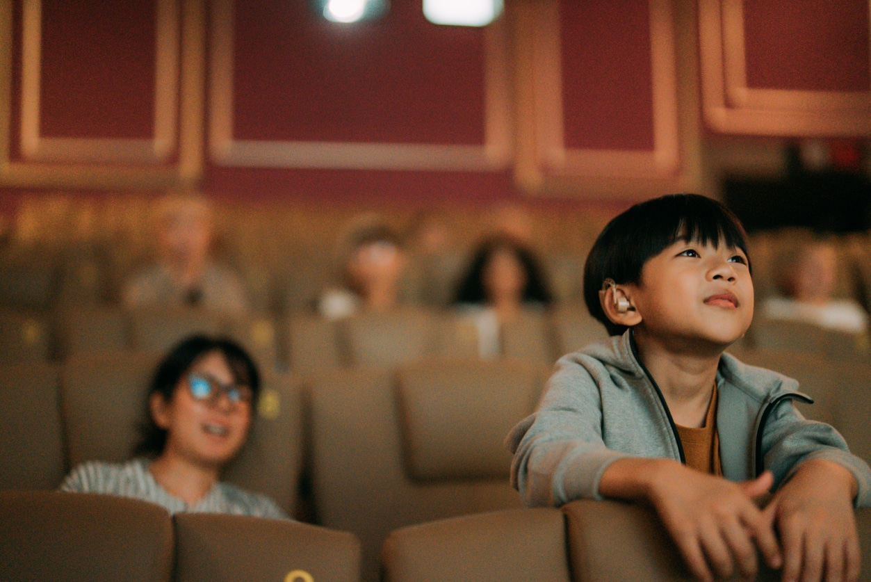 Boy with hearing aids sees a movie