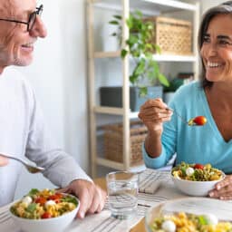 Happy married couple in their home eating a healthy lunch.