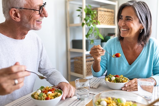Happy married couple in their home eating a healthy lunch.