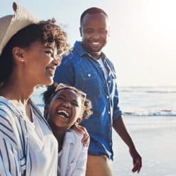 Happy family of three walking along the beach