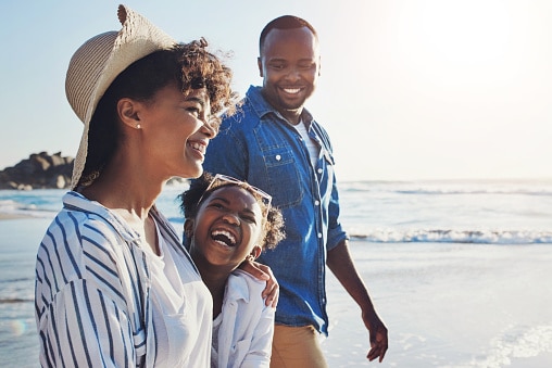 Happy family of three walking along the beach
